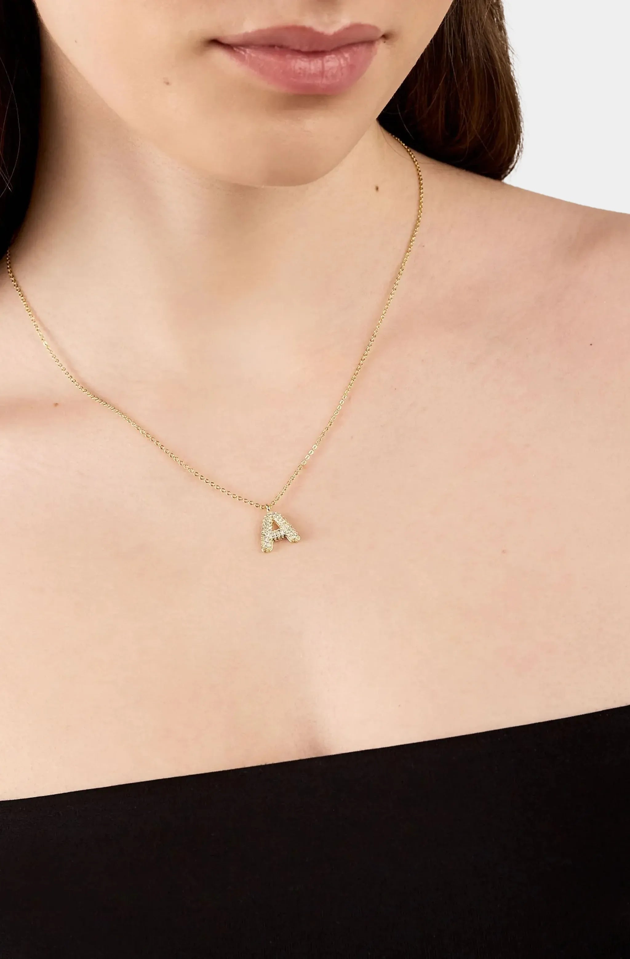 Model wearing gold bubble letter necklace A